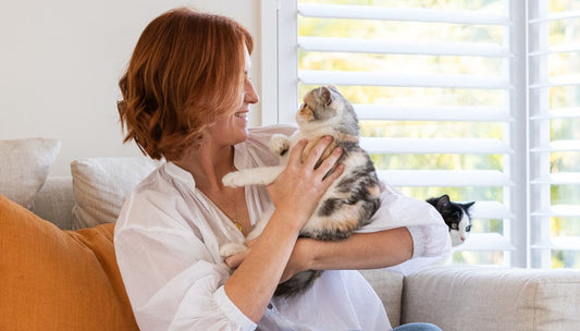 Lady holds and looks into the eyes of her pet after reading about gingivitis in cats